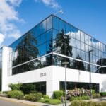Contemporary office building in Redmond with reflective glass and lush greenery, captured on a sunny day.
