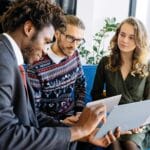 A diverse group of young professionals engaged in a business meeting inside a modern office.