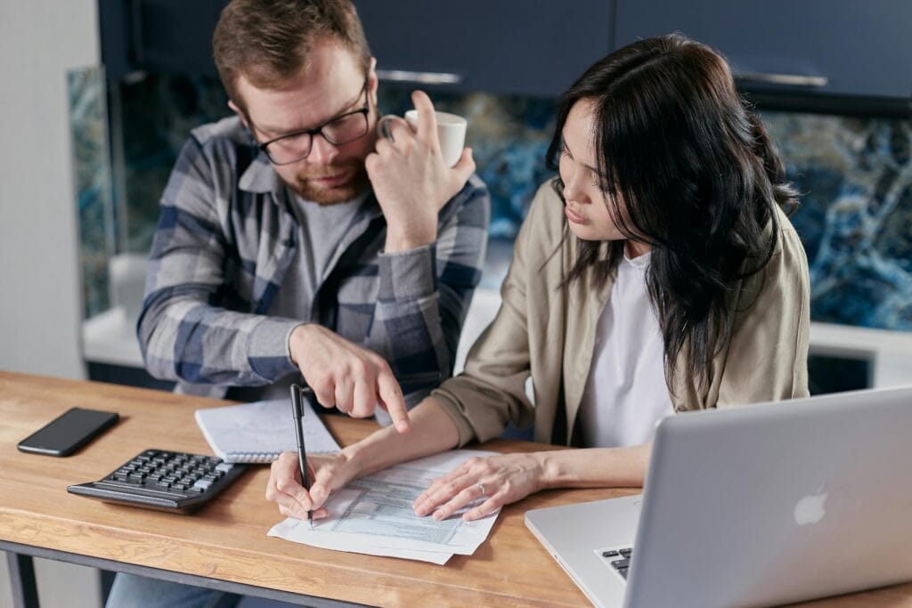 pexels-photo-6964107-6964107 A couple analyzing financial documents with calculator and laptop on a table.