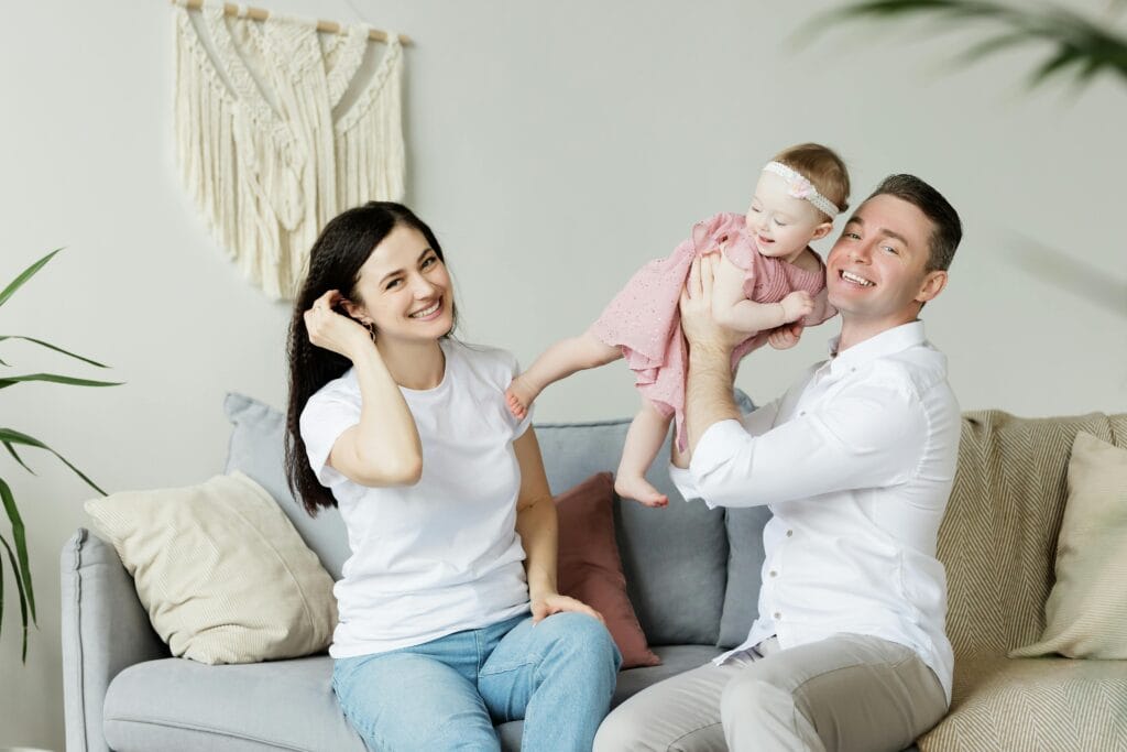MORTGAGE SERVICES 1 Loving parents playing with their baby daughter at home, capturing moments of joy and togetherness indoors.